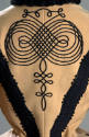 Detail view of tan skating jacket showing black braid and trim on back with spiral design on up…