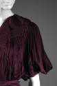 Detail view of purple evening gown showing shirred shoulder yoke with scroll design and puffed …