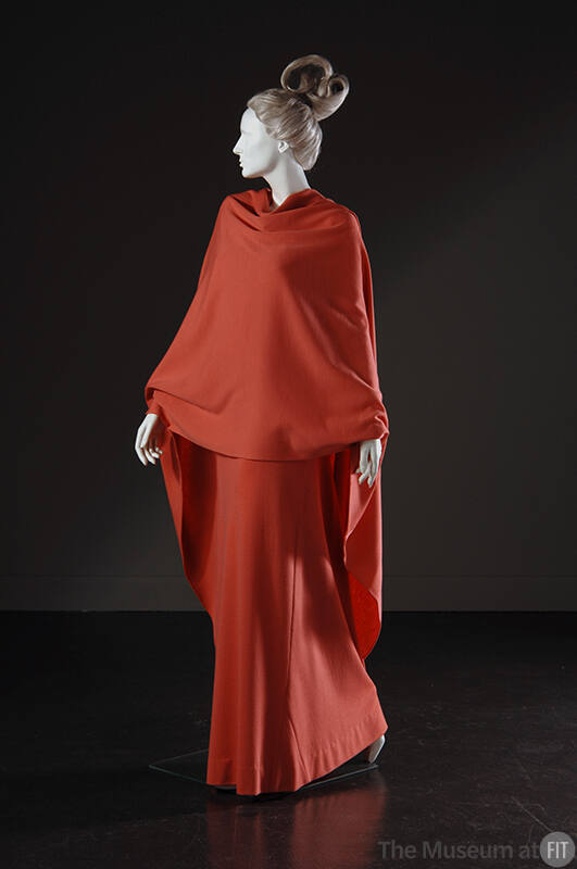 Red orange floor length gown with matching large wrap draped across torso 