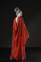 Back view of red orange gown with matching large wrap draped down back to floor 