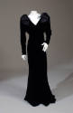 Black velvet floor length V-neck gown with long dolman sleeves and large shoulder bows