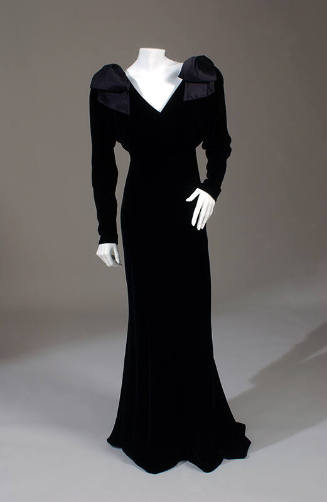 Black velvet floor length V-neck gown with long dolman sleeves and large shoulder bows