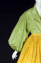 Detail of green blouse with large puffy long sleeve and yellow gathered skirt with waistband 