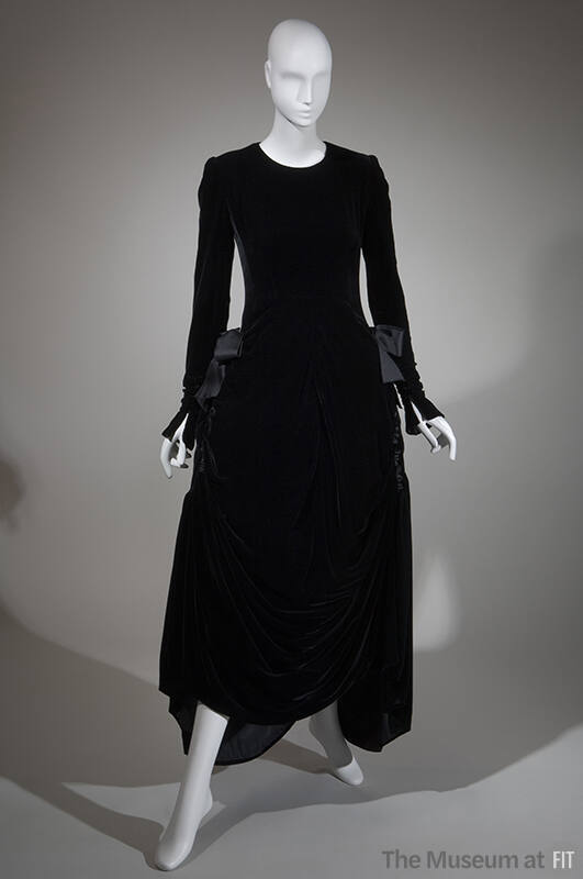 Long sleeve black velvet ankle length dress with large bows at gathered side hips