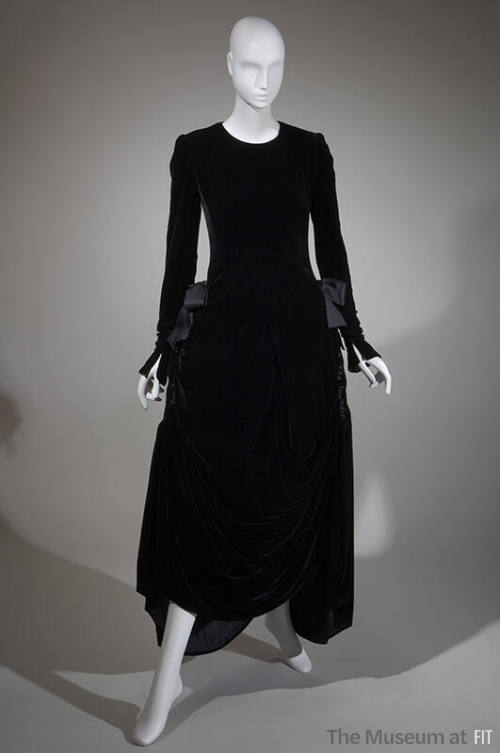 Long sleeve black velvet ankle length dress with large bows at gathered side hips