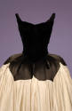 Detail of black velvet bodice with petal shaped hips and off-white skirt