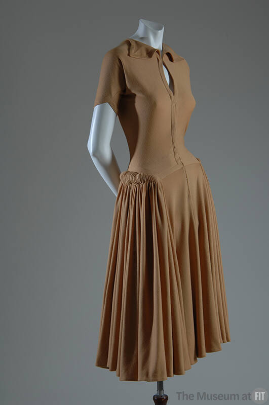 Light brown short sleeve knee length dress with small collar, pleated skirt and hip rolls