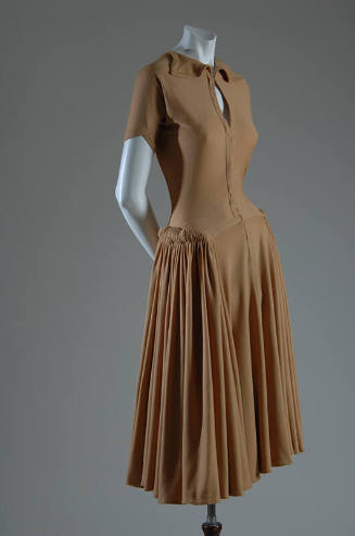 Light brown short sleeve knee length dress with small collar, pleated skirt and hip rolls