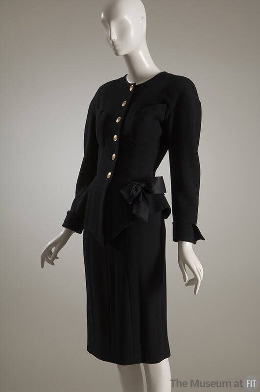 Black wool jacket with gold button front, patch pockets and bow at hip and matching skirt