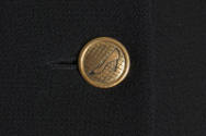 Gold metal button on black fabric with shoe motif 