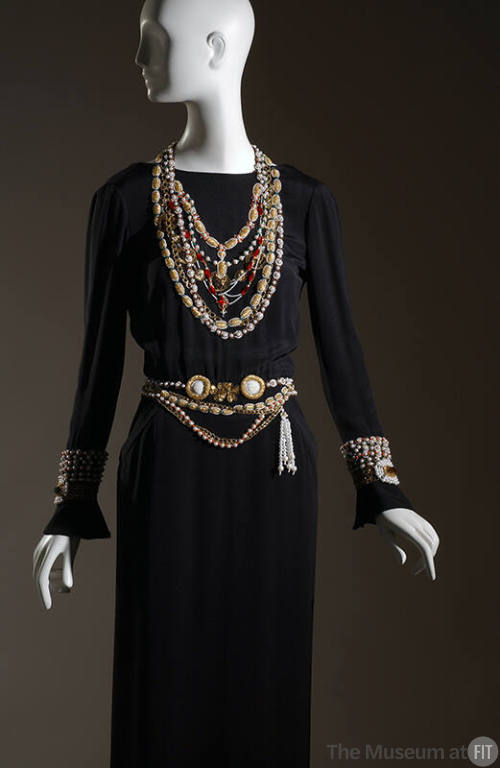 Black long sleeve dress with multiple embroidered necklaces, belts and bracelets