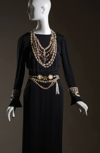 Black long sleeve dress with multiple embroidered necklaces, belts and bracelets