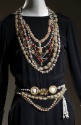 Detail of black dress bodice with multiple embroidered necklaces and belts 