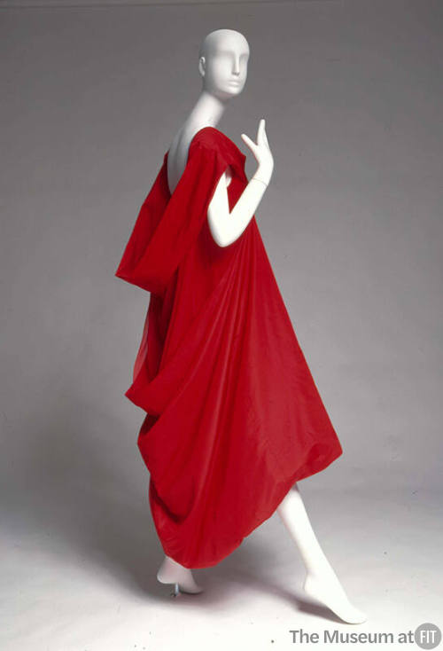 Red evening dress with high front neckline that is doubled, folded and bias cut at the back to …