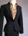 Detail view of black jacket and leopard body suit showing single button front closing and fitte…
