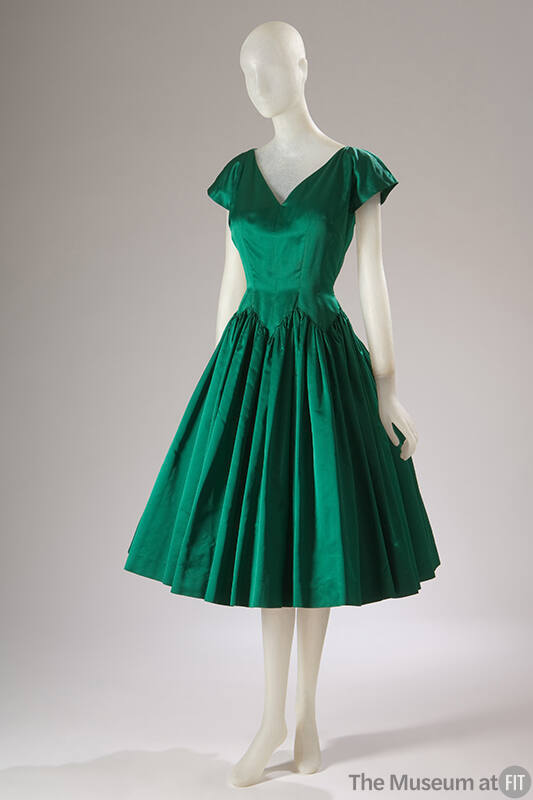 Green knee length cocktail dress with v-neck, cap sleeves and full, pleated skirt with zigzag s…