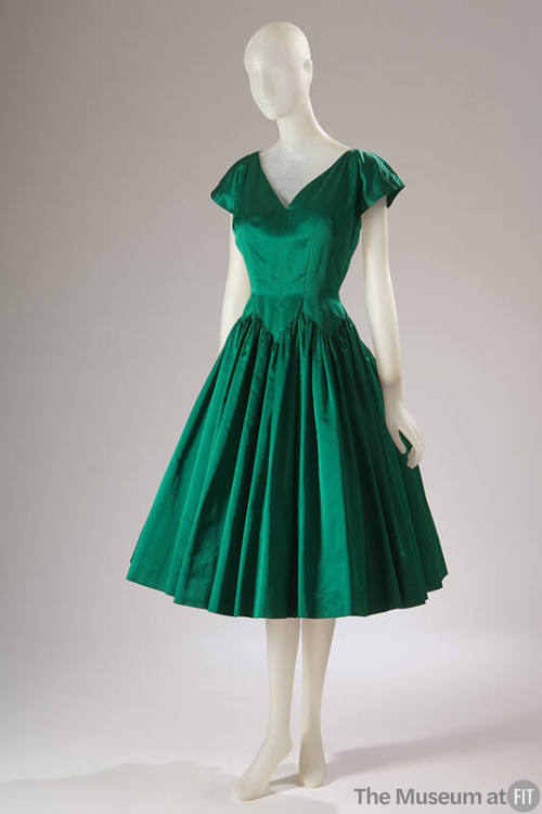 Green knee length cocktail dress with v-neck, cap sleeves and full, pleated skirt with zigzag s…