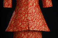 Detail view of red and gold brocade suit novelty seaming and flared bottom of jacket