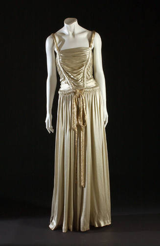 Ivory lamé floor length gown with gold lamé rouleau shoulder straps and tie belt and shirred bo…