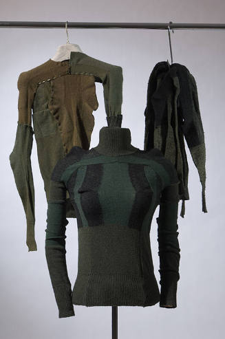 Three hanging long sleeve sweaters in shades of green and black made from socks