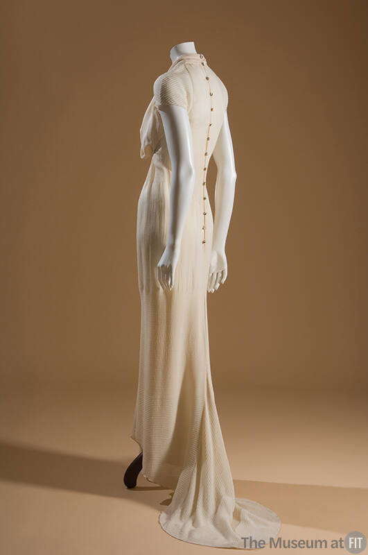 Back view: off white floor length dress, straight skirt with fishtail, and buttons down the bac…