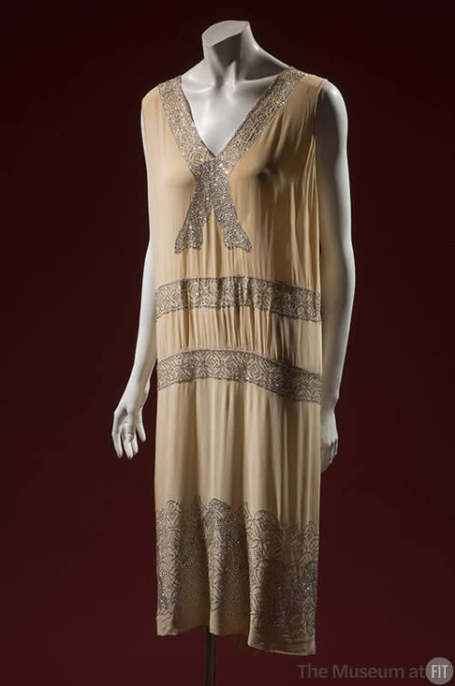 Off-white evening chemise with rhinestone bowknot bands along deep v-neck, wide rhinestone hem …
