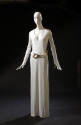 White floor length evening shift dress with V-neck, long sleeves and belt with large buckle of …