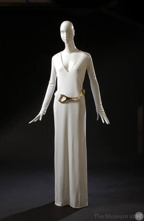White floor length evening shift dress with V-neck, long sleeves and belt with large buckle of …