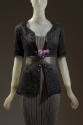Detail view of black jacket and grey dress ensemble showing scrollwork design and ribbon trim o…