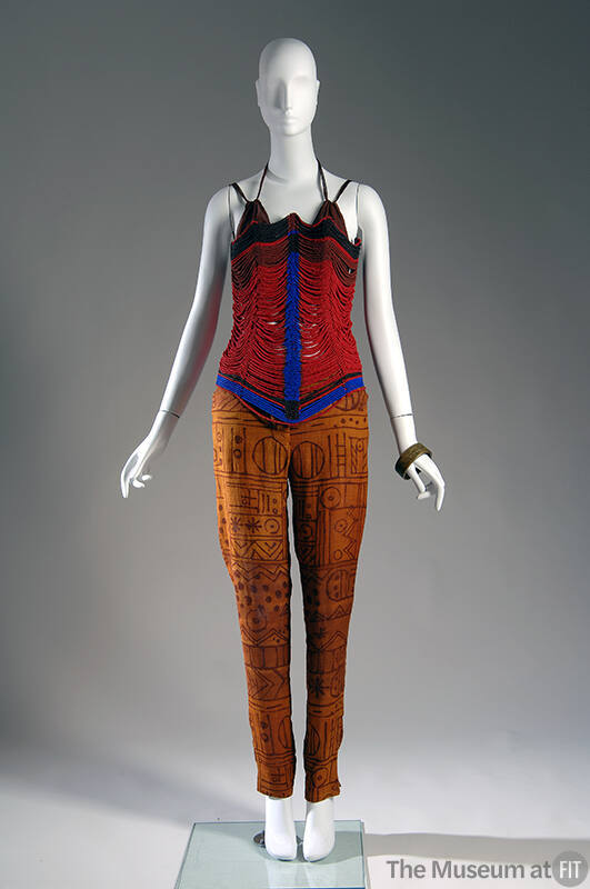 Red corset made of red, blue and brown beads with brown bra top underneath and copper pants wit…