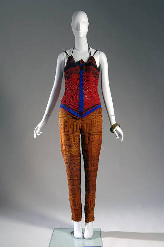 Red corset made of red, blue and brown beads with brown bra top underneath and copper pants wit…