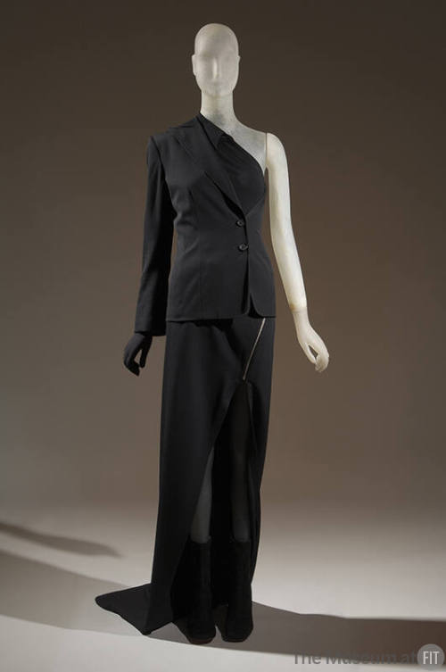 Black ensemble of suit jacket and shirt with one left arm, one left hand glove, long skirt with…