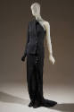 ¾ view of black asymmetrical ensemble showing two-button right of center closure in jacket and …
