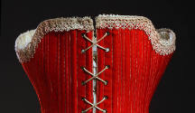 Detail view of back of corset showing white lace at top edge and white lacing closure