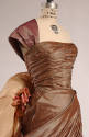 Detail of pinkish gold one shoulder pleated bodice with silk flowers at hip 