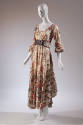 Asymmetrical cream peasant dress with enlarged flower, birds, and dog print with wide belt