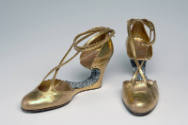 Gold metallic evening shoes with rhinestone encrusted voided arch, wedge, and ankle tie straps