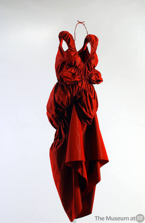 Red, sleeveless, evening dress tapered to ankle length with asymmetrically draped bubble skirt …