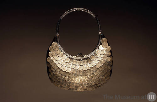 small, brown/black crescent shaped pouch covered with scales of silver metal disks