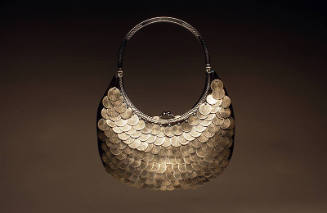 small, brown/black crescent shaped pouch covered with scales of silver metal disks