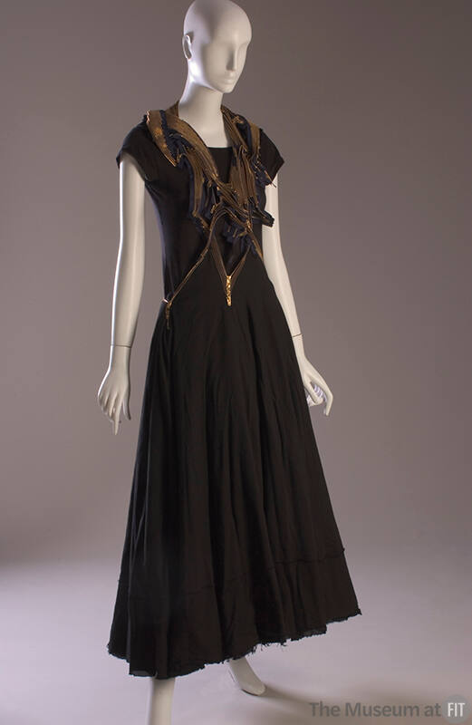 Jumper dress with asymmetrical halter top of multiple gold metal zippers and full black ankle-l…