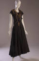 Jumper dress with asymmetrical halter top of multiple gold metal zippers and full black ankle-l…