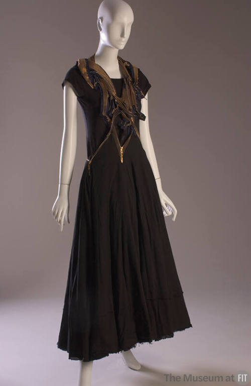 Jumper dress with asymmetrical halter top of multiple gold metal zippers and full black ankle-l…