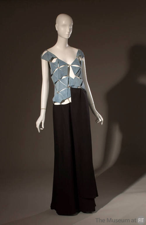 Asymmetrical openwork blue denim bodice linked with metal rings, long flowing black skirt attac…