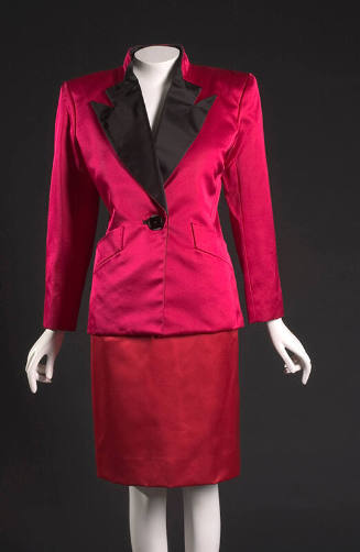 Fuschia jacket with black lapels and single button, padded shoulders; knee length red skirt