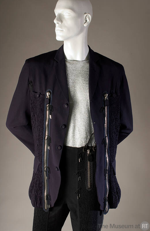 Navy suit fitted with shirred panels on jacet and pants, large silver zippers, trimmed with sho…