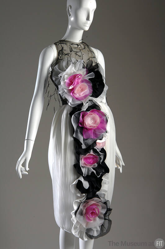 Sleeveless below-the-knee dress with sheer black bodice, pleated white skirt and large pink, bl…
