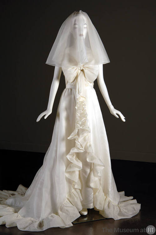 Off-white wedding dress with large bow bodice and ruffled trim down front and around hem with t…