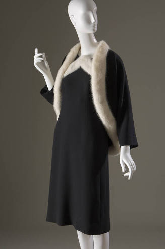Black knee length dress and matching short jacket, both with white fur trim 