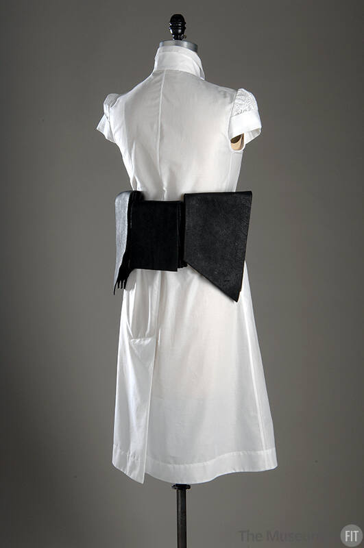 Back view of white cap sleeve to-the-knee dress with wide black leather layered belt